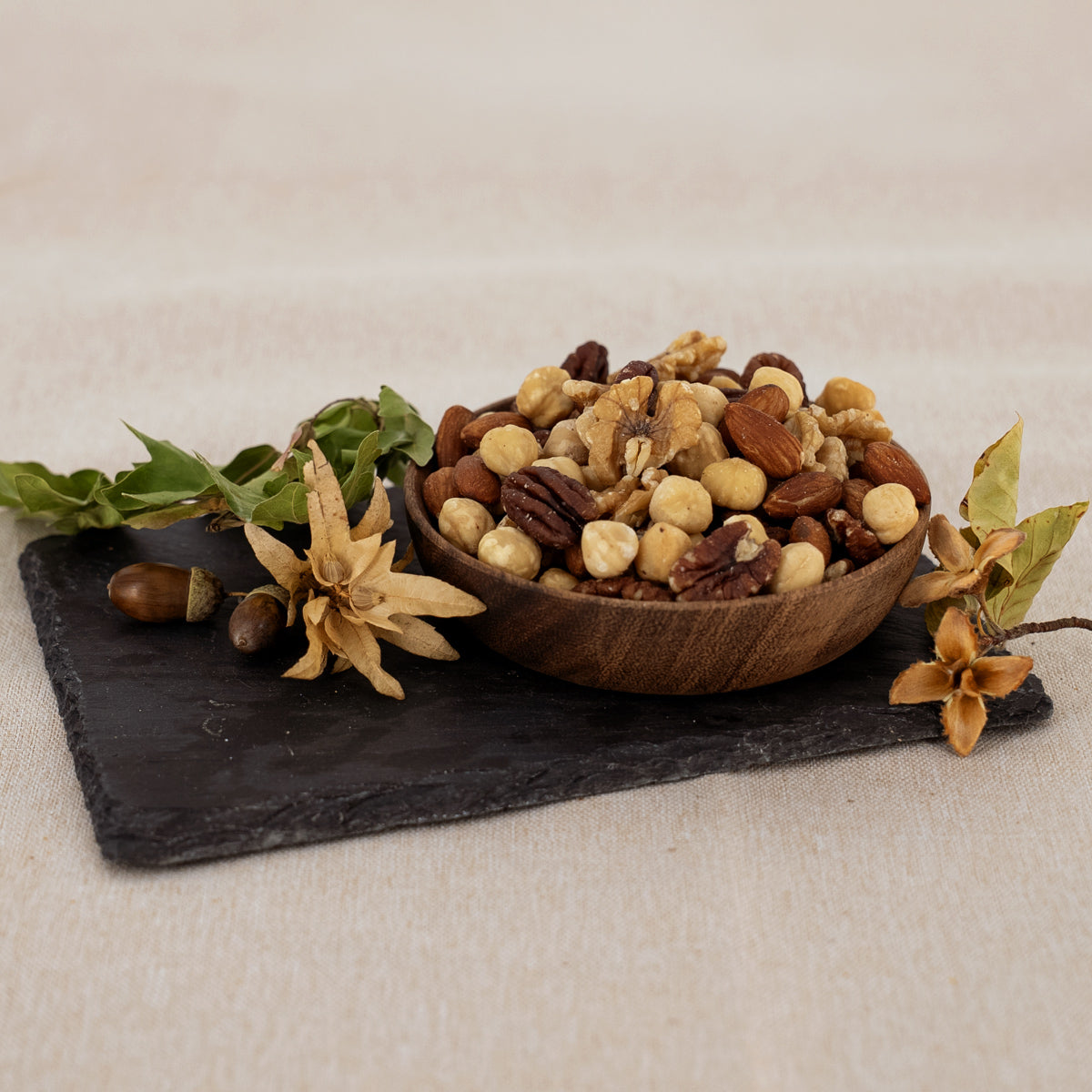Nussmischung Eichhörnchen mit Walnüssen, Pekannüssen, Haselnüssen und Mandeln in Holzschale und herbstlich dekoriert