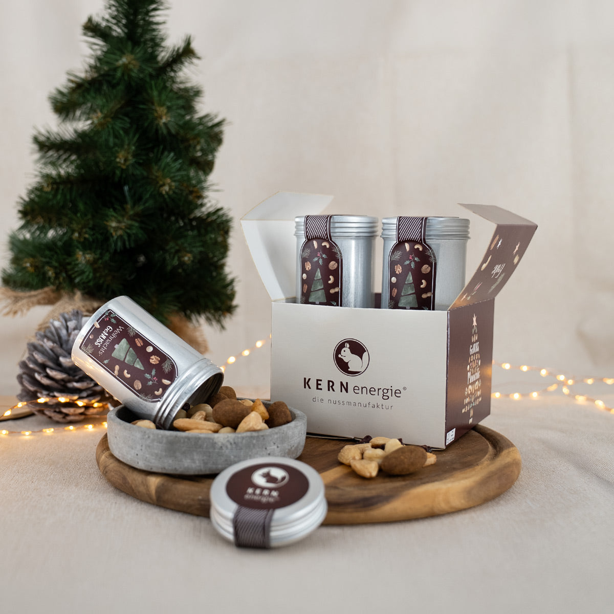 Kleines Weihnachtsgeschenk-Set mit vier Aludosen im weihnachtlichen Design und einer Nussmischung im einer Steinschale