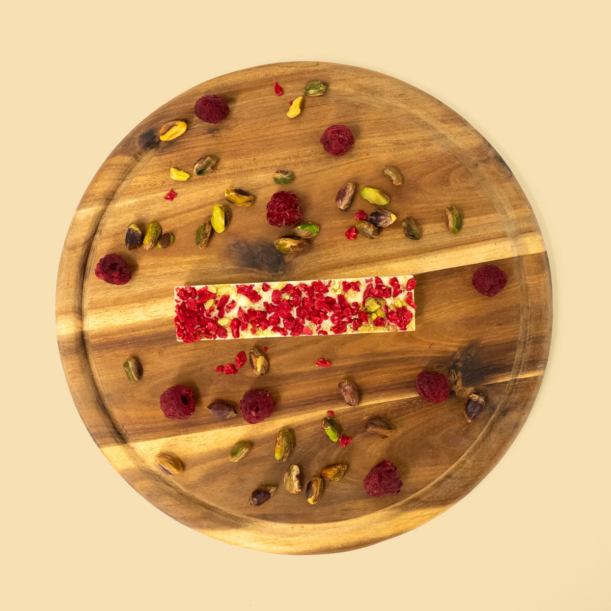 Schokoriegel mit weißer Schokolade, Pistazien und Himbeeren auf Holztablett