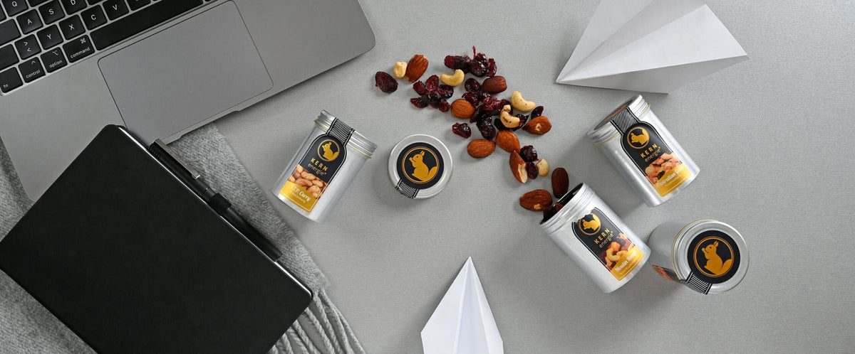 frisch geröstete Nüsse in der Aluminiumdose als Brainfood neben Macbook und Terminplaner