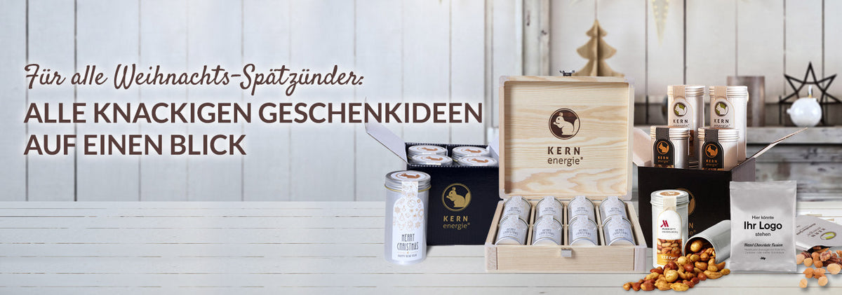 Verschiedene weihnachtlich verpackte Geschenkideen von KERNenergie: Aludosen mit Nüssen, individualisierbare Geschenkkartons und X-Mas-Holzboxen als hochwertige Weihnachtsgeschenke für Kunden, Mitarbeitende und Geschäftspartner.