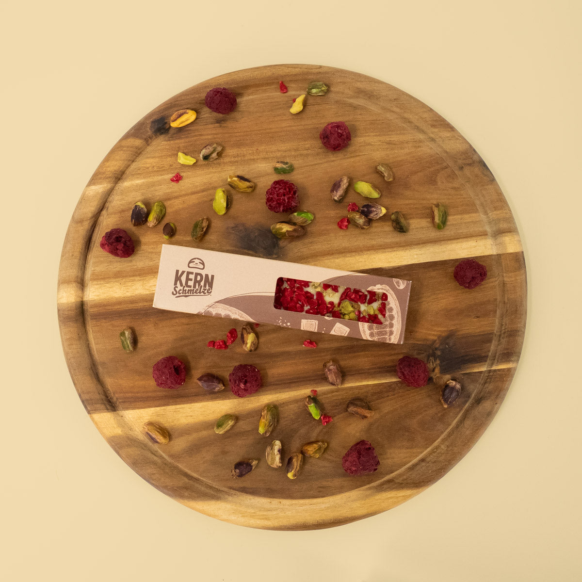 Schokoriegel mit weißer Schokolade, Pistazien und Himbeeren in Standardverpackung auf Holztablett