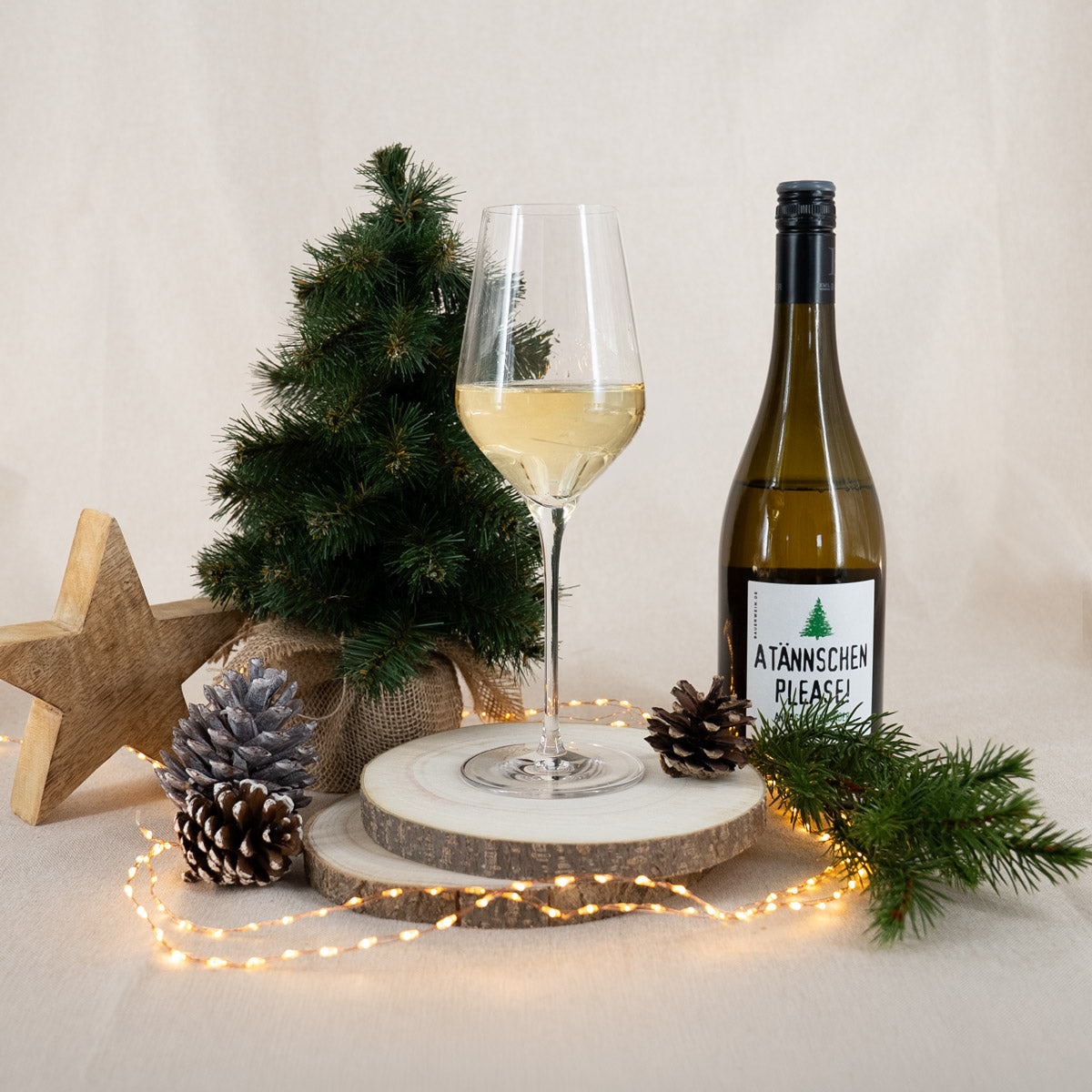 Befülltes Glas Weißwein und Weißweinflasche "A Tännschen Please" mit weihnachtlicher Dekoration