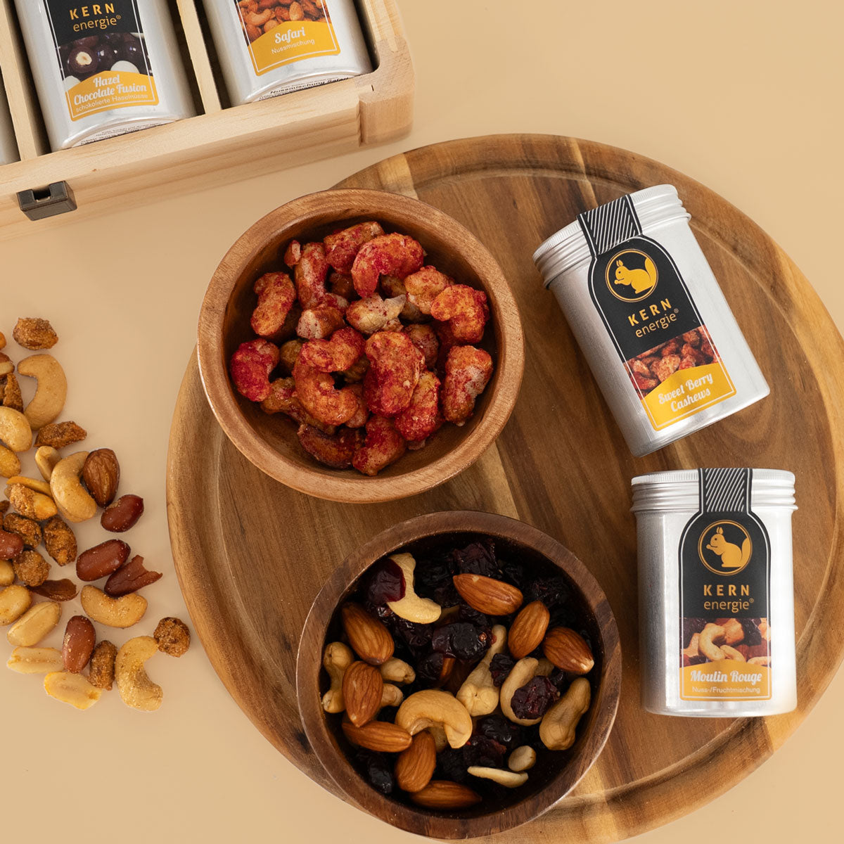 Gebrannte Cashewkerne und eine Nuss-Frucht-Mischung in Holzschalen mit zwei hochwertigen Aludosen daneben