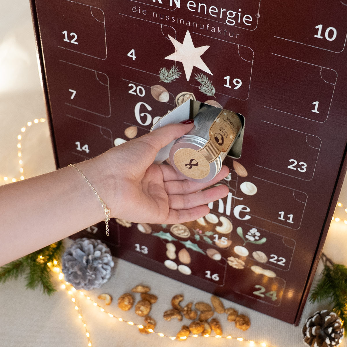 Adventskalender in klassischer Form mit geöffnetem Türchen, aus dem eine weihnachtliche Aludose genommen wird.