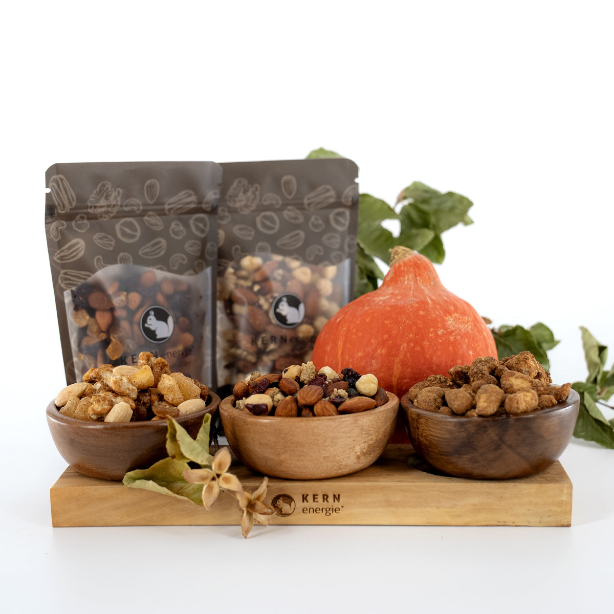 Nussmischungen und gebrannte Cashewkerne in Holzschalen und herbstlicher Deko